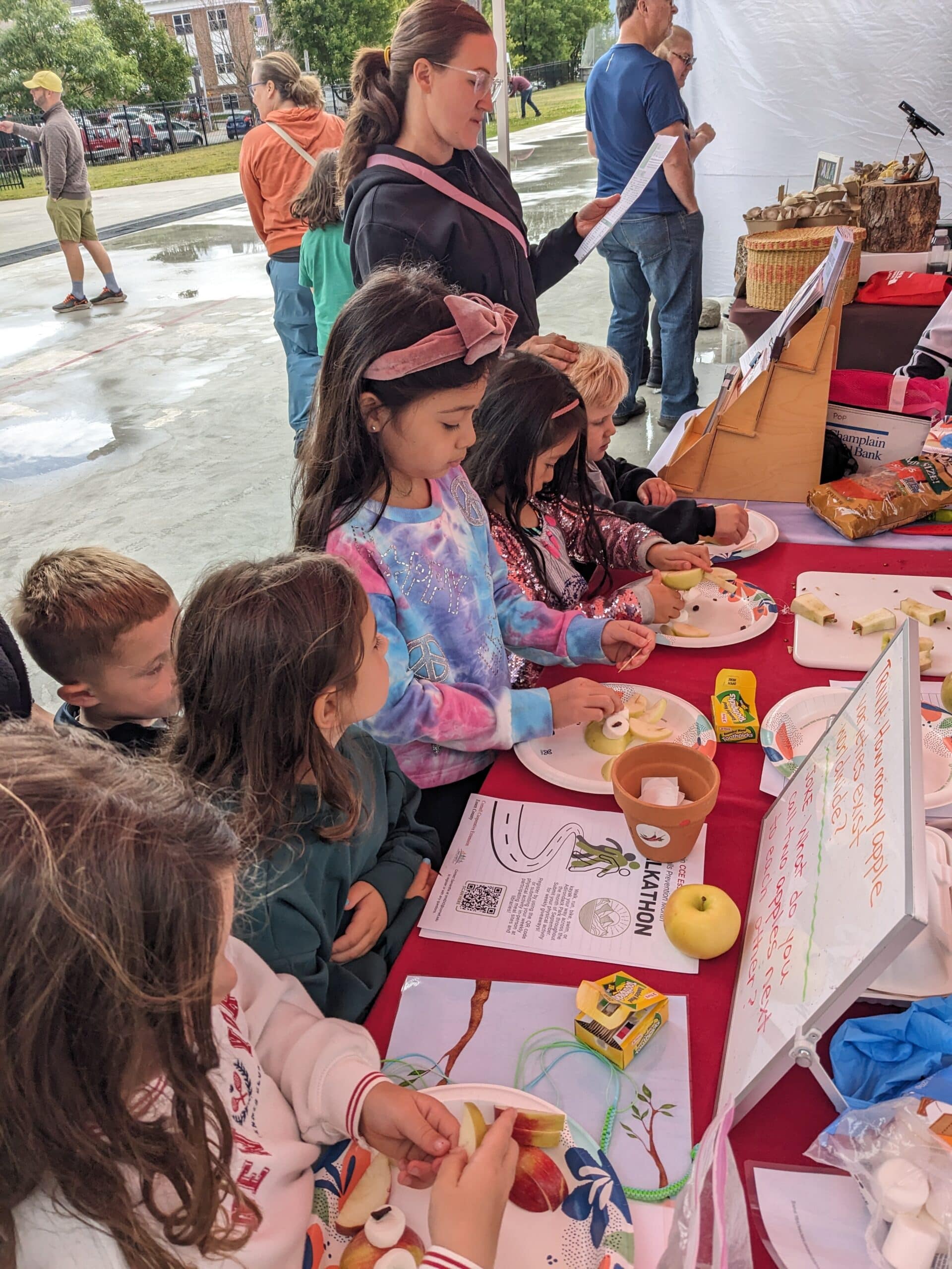 Kids gather around the POP Club booth's table to assemble apple owls.