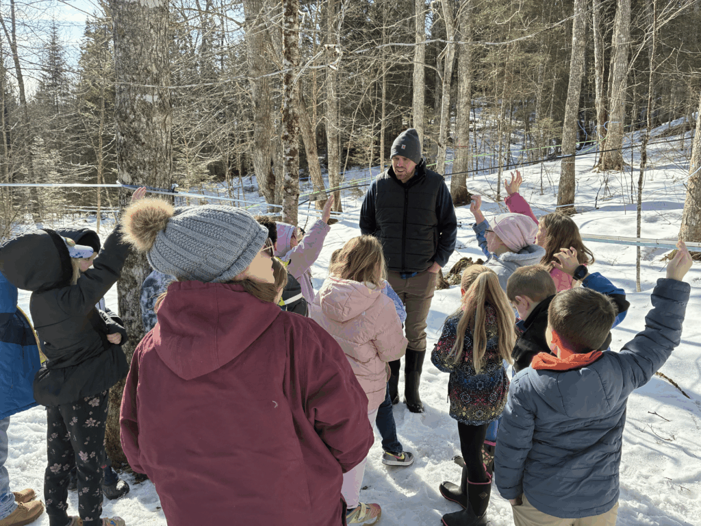 Adam Wild with AuSable Forks second grade students in the sugarbush. Photo by Liz Donahue.