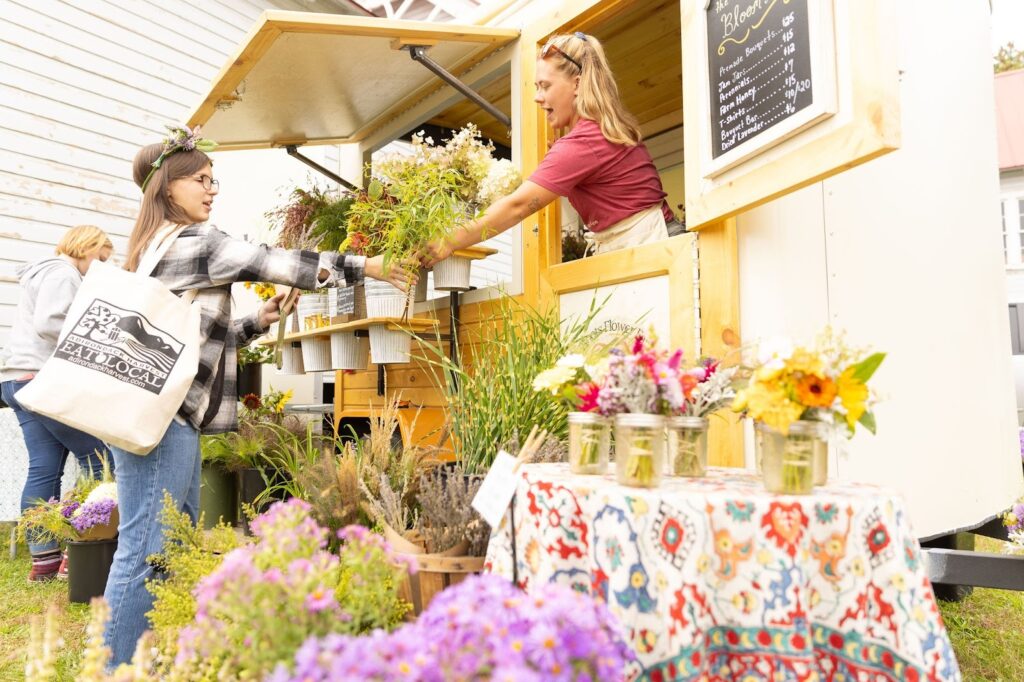 A woman is buying flowers from a flower cart at the Adirondack Harvest Festival. 