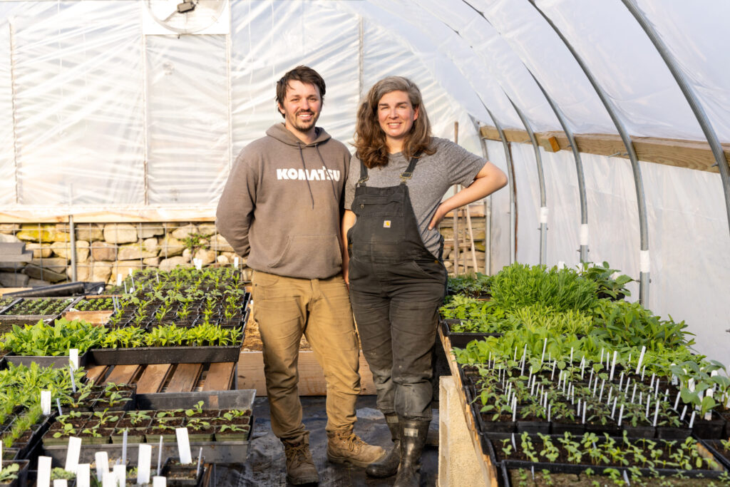 Two people in greenhouse with seedlings