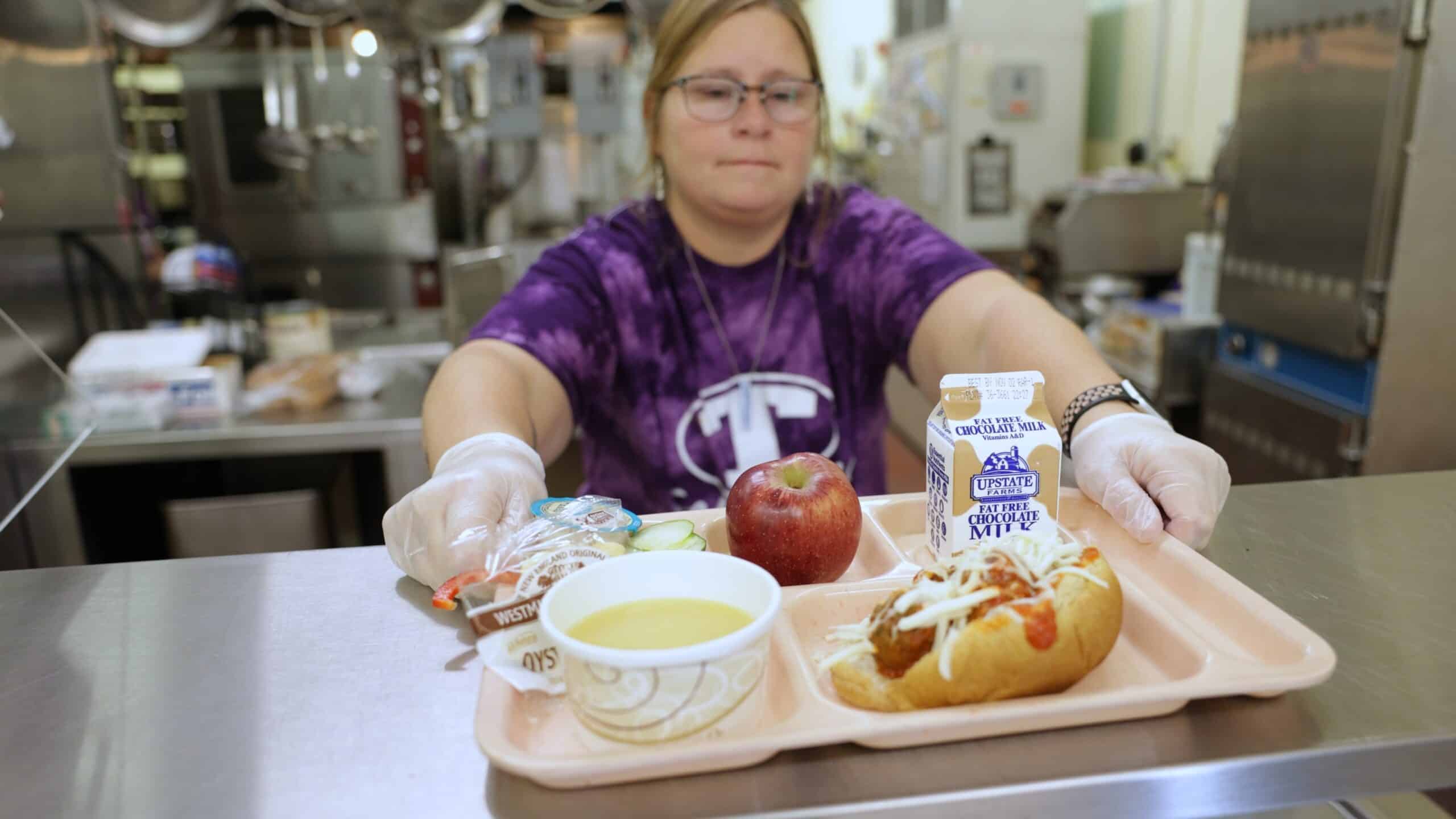 Cafeteria worker serving a tray of food