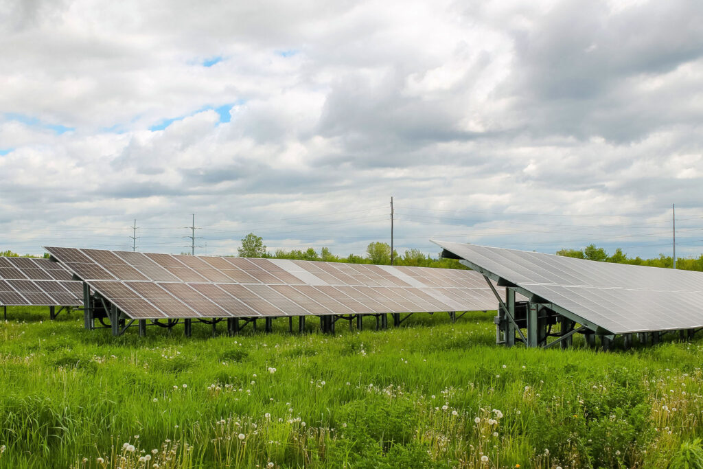 Solar panels in a green field under cloudy sky