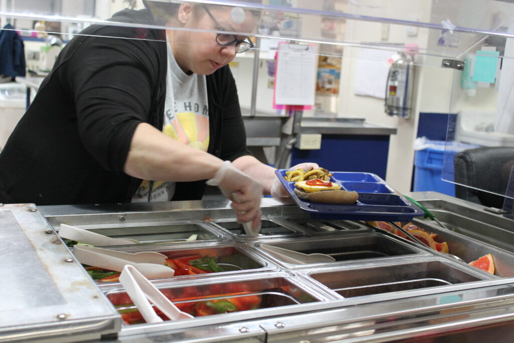Person serving food on tray in cafeteria