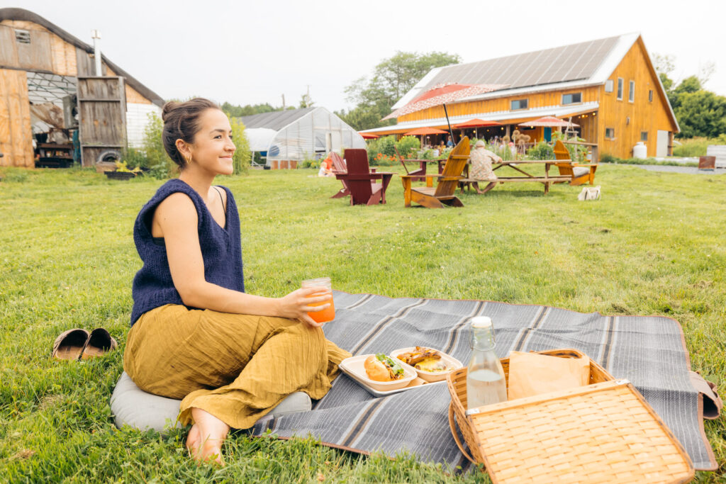 Woman picnicking on a farm with food and drinks