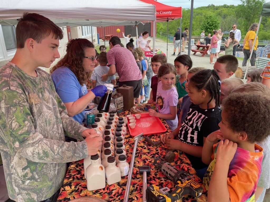 Children sampling maple syrup at outdoor event