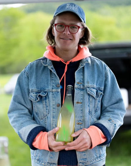 Person holding a glowing green bottle outdoors