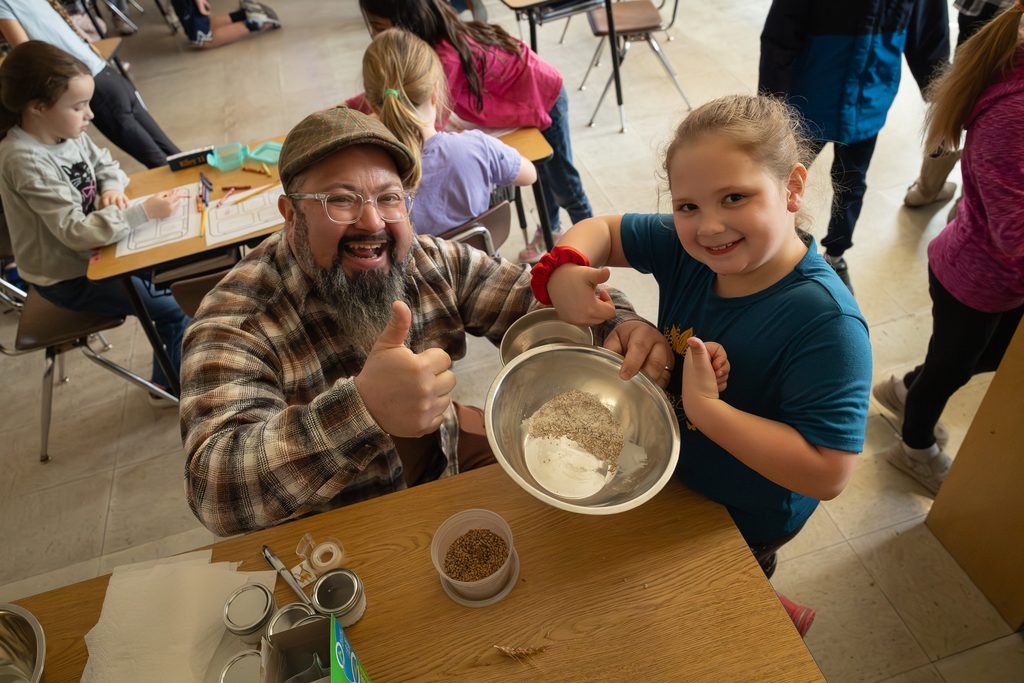 Man and girl mixing ingredients in a classroom