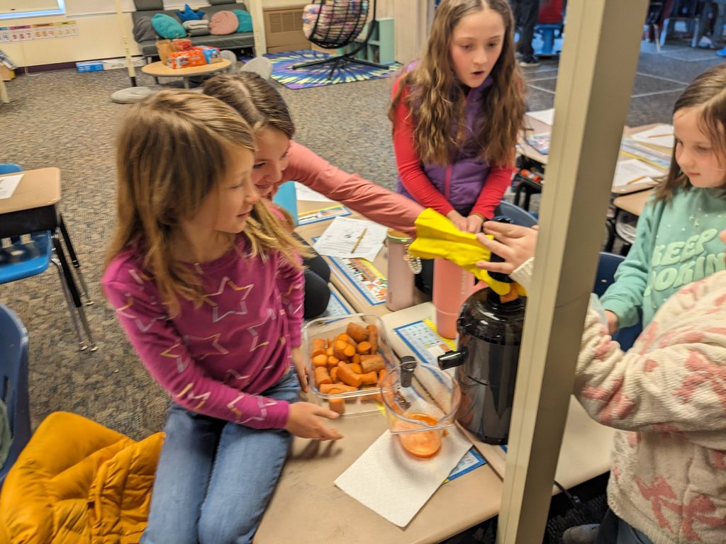 Children making smoothies with carrots in classroom