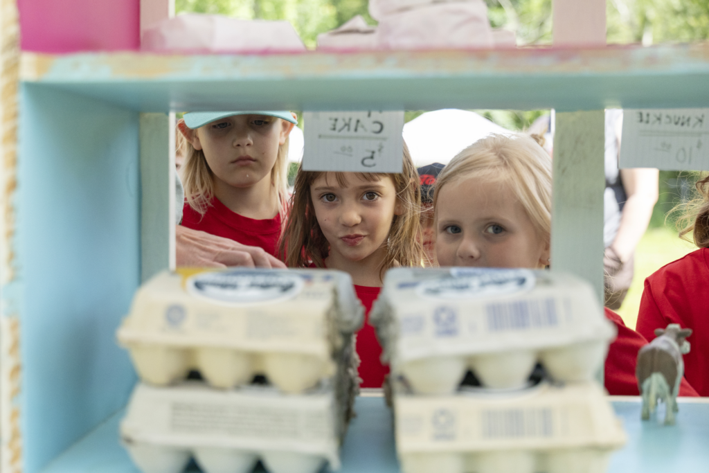 Children selling eggs at a colorful outdoor stand