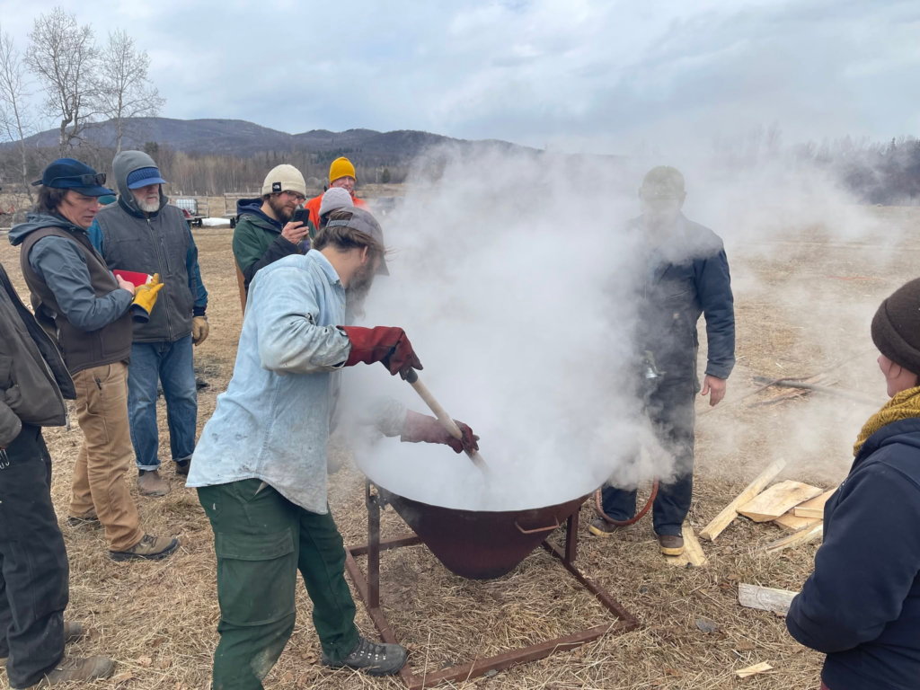 People boiling sap for maple syrup outdoors
