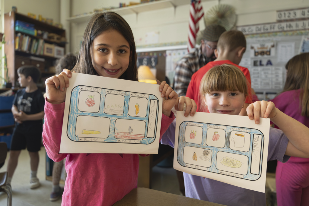 Children holding artwork in classroom