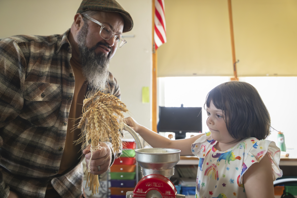 Man and child grinding wheat in a manual grain mill