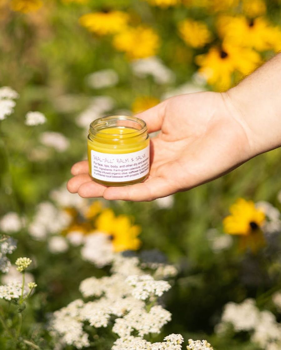 Hand holding yellow cream jar in flower field